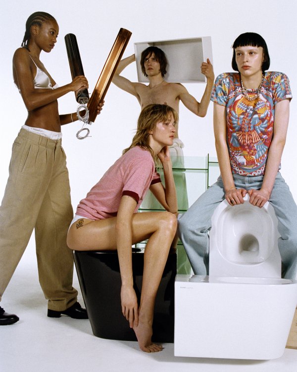 Vier bunt gekleidete junge Menschen sitzen auf oder stehen rund um ein schwarzes und ein weisses WC der Kollektion Kartell by Laufen.
