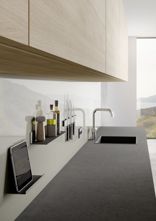 Glänzende Küchenrückwand mit Holzschränken darüber. An der Wand sind ein Regal mit einem iPad, eines mit Gewürzen und Öl und eine Leiste mit Messer magnetisch festgemacht.