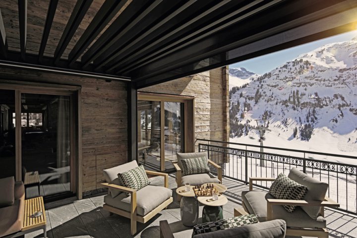 Aussicht in Schneelandschaft von der überdeckten Terrasse eines Chalets.