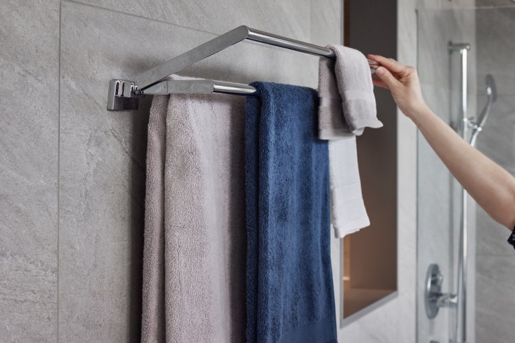 Silberne Mehrfachbadetuchstange an einer grauen Fliesenwand im Bad, an der ein graues, blaues und weisses Badetuch hintereinander genügend Platz finden.