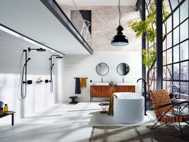 Grosszügiges, modernes Bad mit Wand mit zwei Duschen links, einer freistehenden Badewanne in der Mitte und einem industriellen, bodenlangen Fenster rechts mit Ausblick über die Stadt