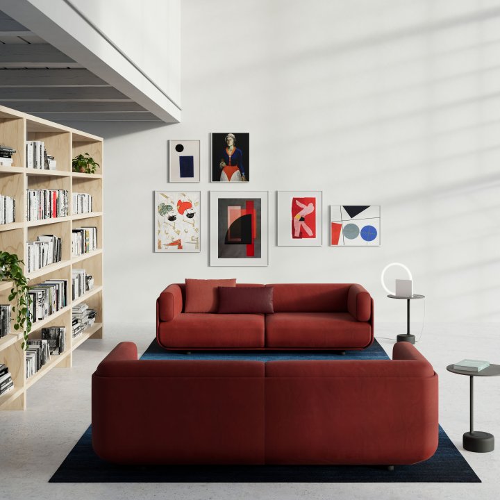 Dunkelrotes Sofa in hohem, hellen Raum mit gefülltem Bücherregal