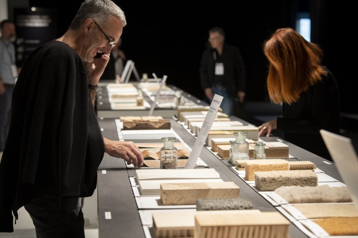 Messe-Besuchende über über Materialmuster aus Holz gebeugt