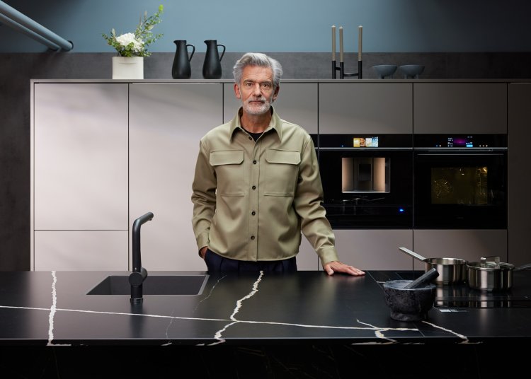 Alfredo Häberli steht in moderner grauer Küche mit schwarzer Abdeckung aus Marmor.