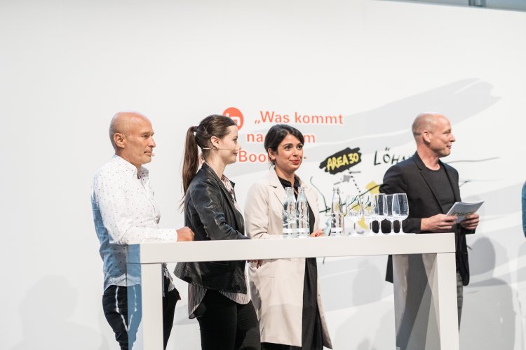 Podiumsdiskussion mit zwei Frauen und zwei Männern hinter weissem Tisch