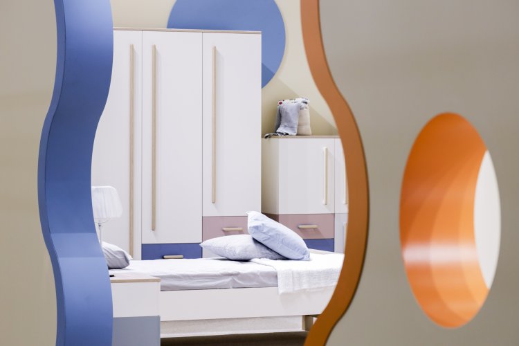 Durchblick durch organische Öffnung zu hell eingerichtetem Schlafzimmer