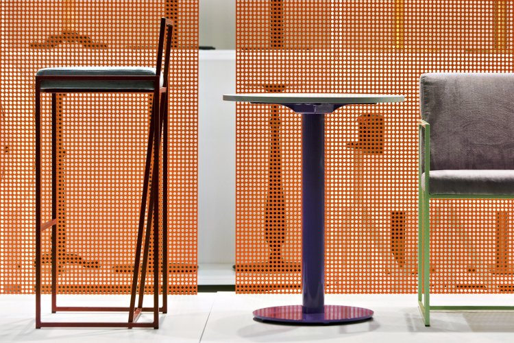 Barchocker, Bistrottisch und Stuhl vor oranger Lochwand