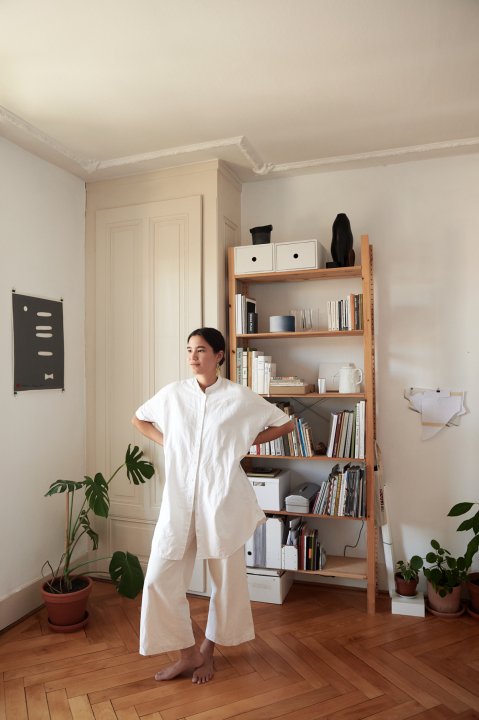 Noelani Rutz steht in weissen, lockeren Kleider in gemütlichem Zimmer mit Holzboden und Bücherregal
