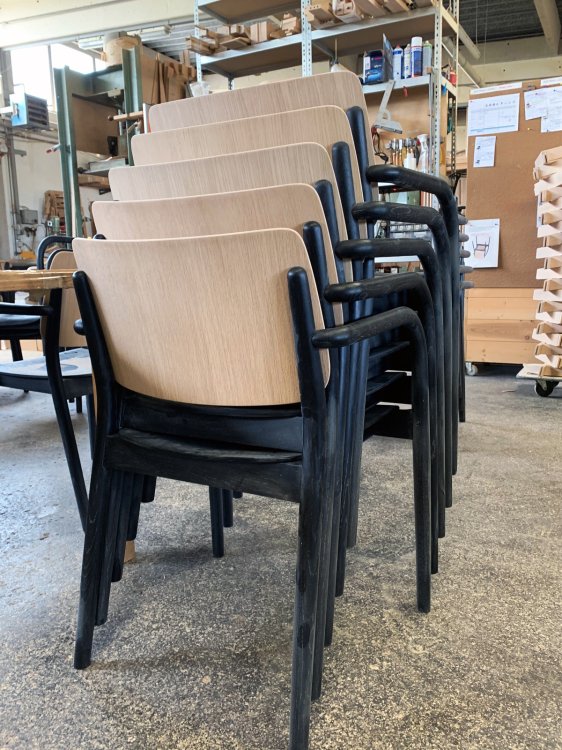 Ein Stapel Holzstühle in einer Fabrikhalle.