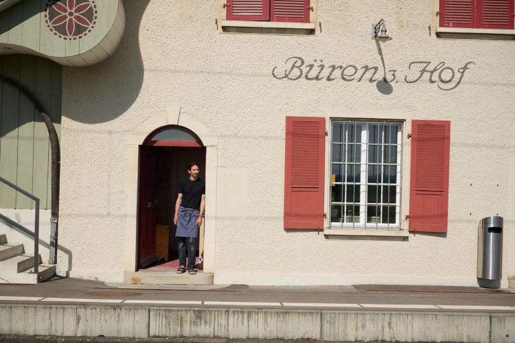 Laurin Schaub steht in der Tür eines alten Bahnhofgebäudes, rechts davon ein Fenster mit roten Fensterläden