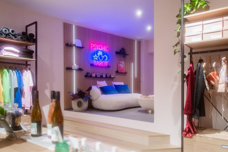 Blick auf ein weisses, rundes Sofa, darüber eine Leuchtanzeige in Pink und Blau