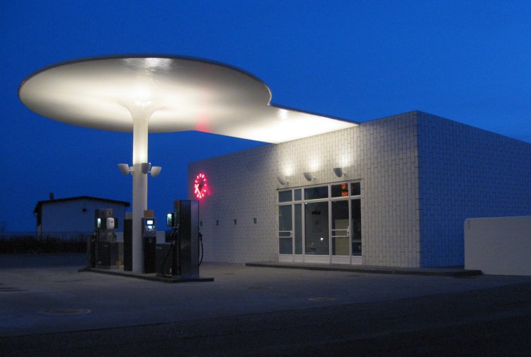 Beleuchtete Tankstelle von Arne Jacobsen im Dunkeln.