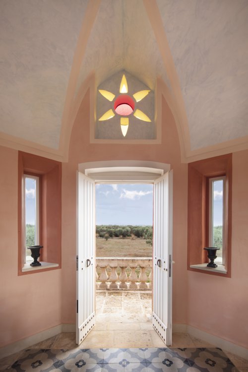 Ausblick aus einem spanisch-maurische Turm mit buntem Glasfenster in Blumenform auf italienische Olivenhaine