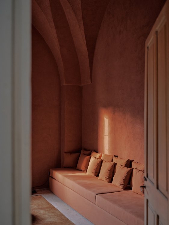 Raum mit gotischen Sternbögen in Terracotta, mit Sofa und Kissen in der gleichen Farbe wie die Wände