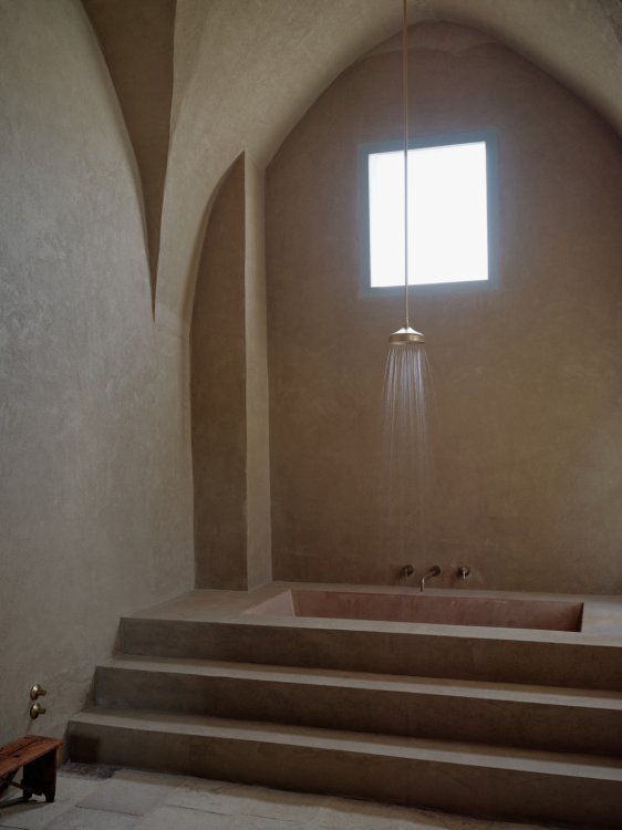 Hängende Dusche über einem Bad mit Treppe zum Einstieg.