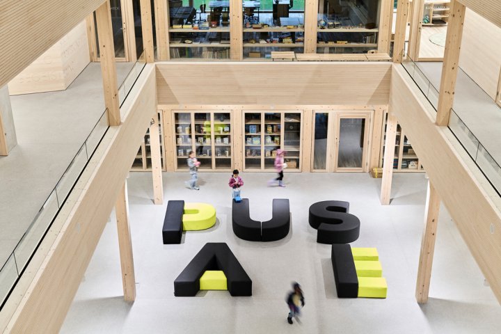 Innenhof einer Schule mit Bänken in dunkelgrau und neongelb, die das Wort Pause formen