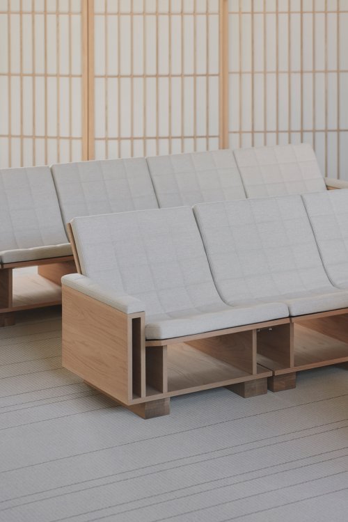 Nahaufnahme von hellen Holz-Sitzbänken mit cremeweissen, gesteppten Polstern im «Listening Room». Das Design zeichnet sich durch architektonische Holzstrukturen aus, die im Hintergrund von filigranen japanischen Raumteilern (Shoji-Sytle) ergänzt werden.