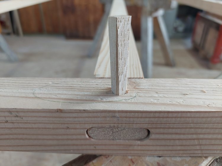 Detailaufnahme einer traditionellen Holzverbindung mit Zapfen und Holznagel in einem Eschenholzbalken.