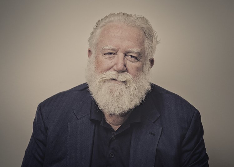 Porträtaufnahme des Künstlers James Turrell: Ein älterer Mann mit vollem weissem Haar und langem weissem Bart blickt direkt in die Kamera vor hellem, neutralem Hintergrund.