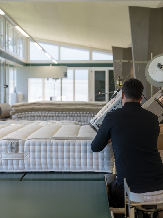 Mitarbeiter in der Elite-Manufaktur arbeitet an einer Matratze an einer Produktionsmaschine.