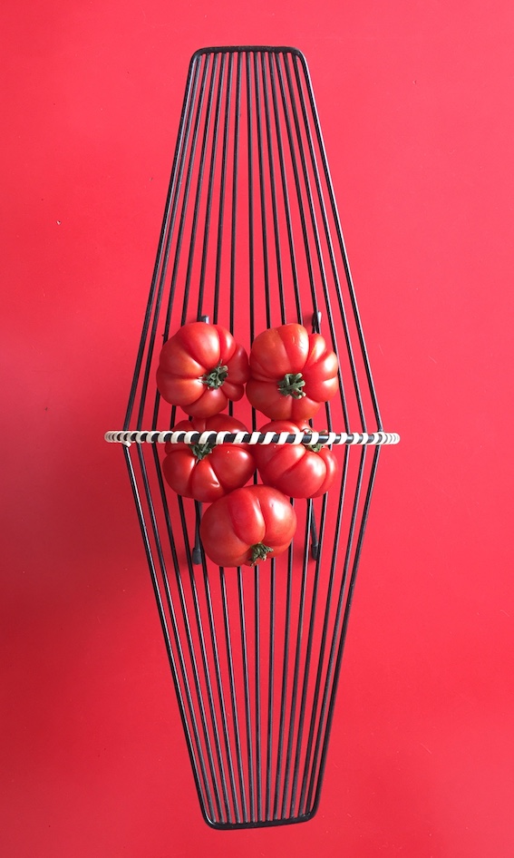 Korb mit Tomaten auf rotem Tisch