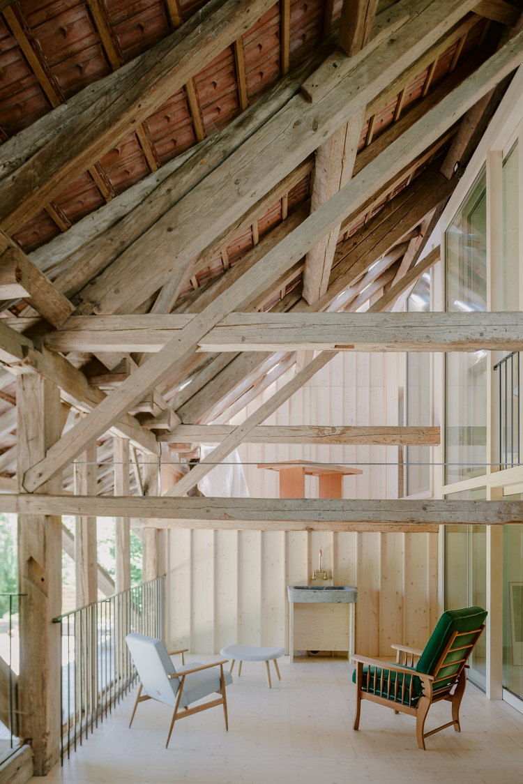 Altes Gebälk, zwei Sessel in einem halboffenen Wohnbereich