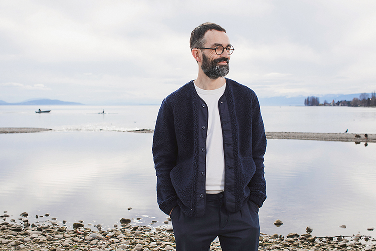 Porträtfoto von einem Mann mit einem weissen T-Shirt, einer dunklen Jacke und Hose