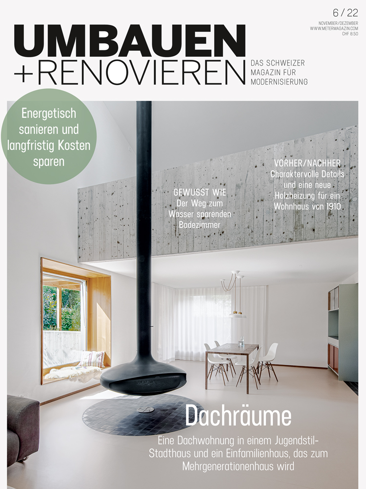Magazin-Cover der aktuellen Ausgabe von Umbauen + Renovieren mit einem offenen hellen Wohnraum mit von der Decke hängendem schwarzen runden Kamin.