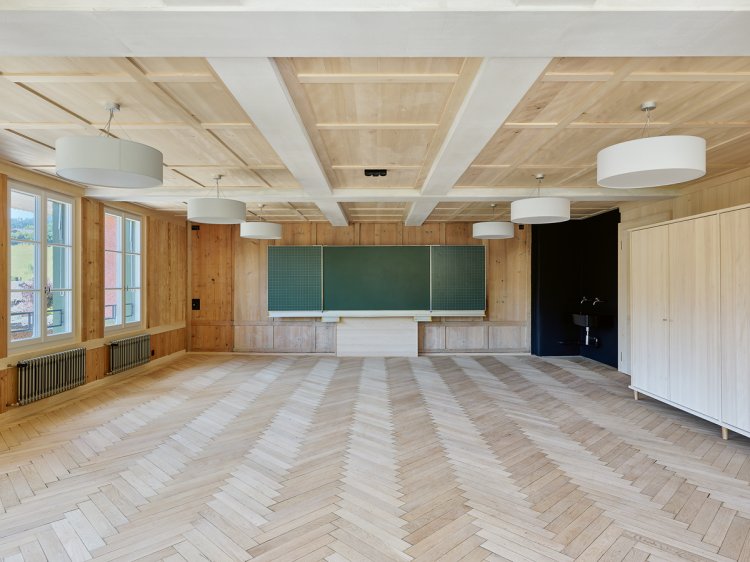 renoviertes Schulzimmer mit viel Holz und einer Wandtafel