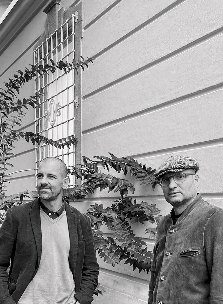 Porträtfoto von zwei Männern vor einem Gebäude