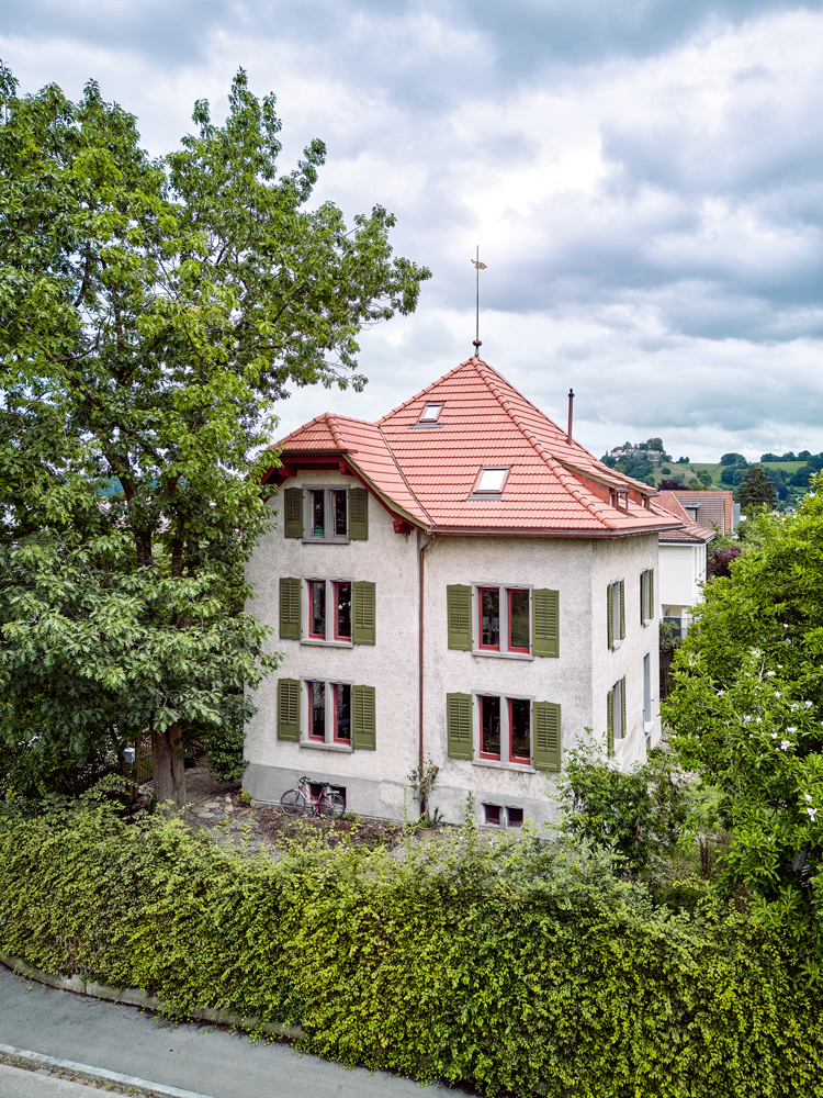 ein Jugendstilhaus mit drei Etagen und einem roten Dach