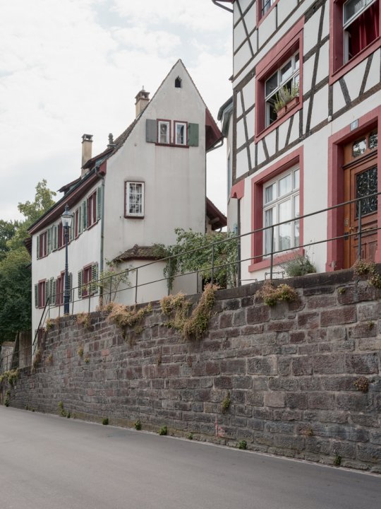 ein schmales altes Haus oberhalb einer Mauer