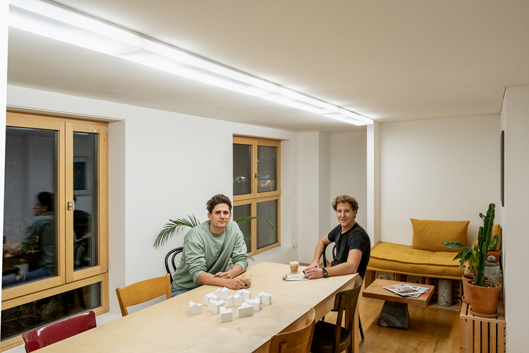 zwei junge Männer an einem Tisch in einem Büro, Architekturmodelle auf Tisch