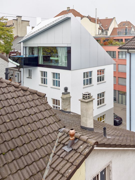 Über die Dächer fotografiertes Stadthaus mit einem auffallenden Dach und einem schwarzen Balkon