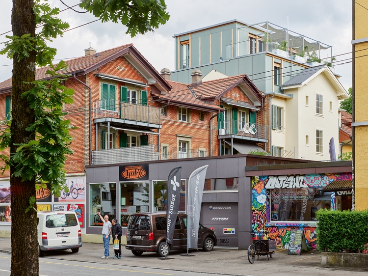 Rückansicht von mehreren städtischen Wohnhäusern, von denen das mittlere renoviert ist und eine neue Fassade hat