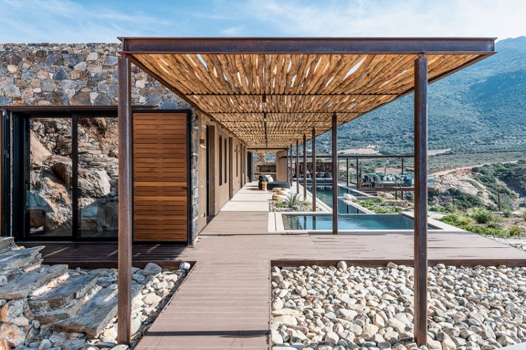 Eine Pergola mit Stahlkonstruktion und Holzbedeckung ist dem länglichen Haus auf Kreta vorgelagert.