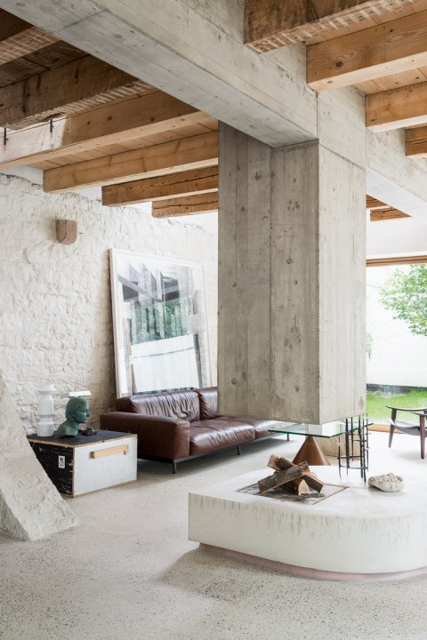 Blick ins offene Wohnzimmer mit hängendem Kamin aus Beton, der Boden und die Wand sind ebenfalls aus Beton.