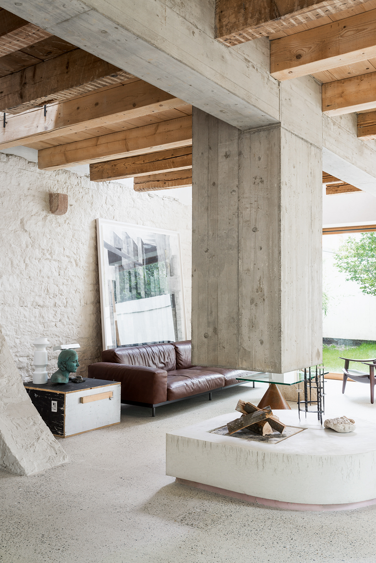 Blick ins offene Wohnzimmer mit hängendem Kamin aus Beton, der Boden und die Wand sind ebenfalls aus Beton.