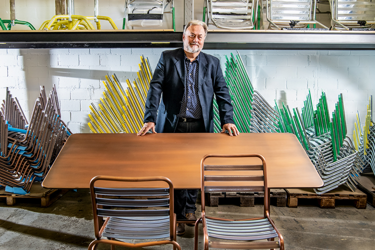Porträtbild von Rainer Hesselbarth stehend hinter einem Bättig-Klassiker Tisch und Stühlen.