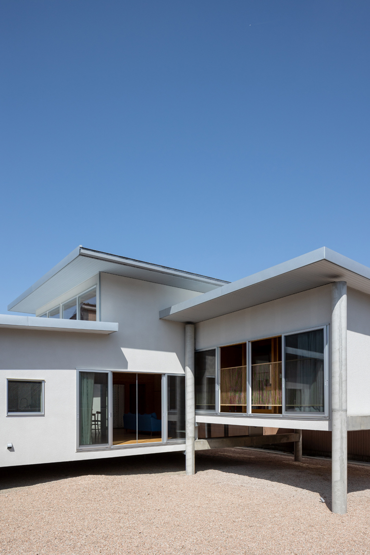Ansicht eines Hauses in Toyama, Japan, das auf Stelzen gebaut ist und zwei unterschiedliche Höhen hat.