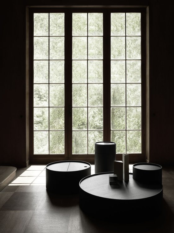 Tisch-Kombination «Moon» von Living Divani in einem dunklen Raum mit hohen Fenstern.