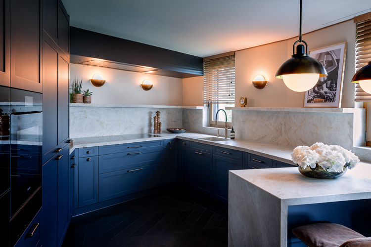 Blick in L-förmige Küche mit blauen Küchenschränken und weisser Oberfläche.