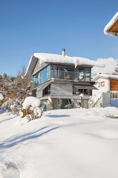 Modernes Giebeldachhaus ist in Schneelandschaft eingebettet.