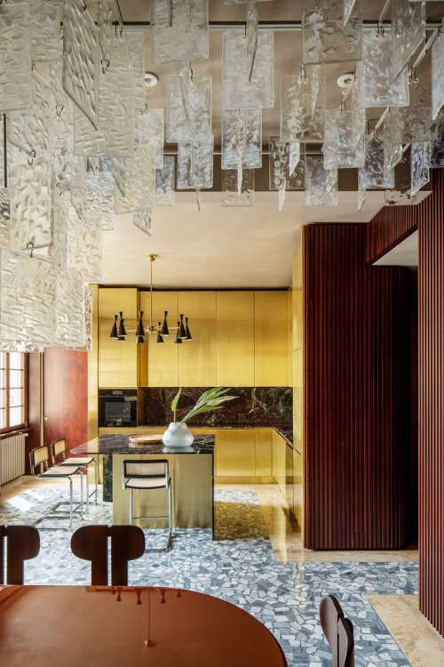 Blick in die offene Küche mit goldenen Küchenschränken.