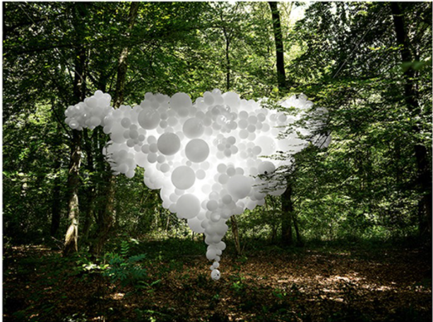 Fotografie von einer wolkenartiger weisser Skulptur in der Luft in einem Wald.