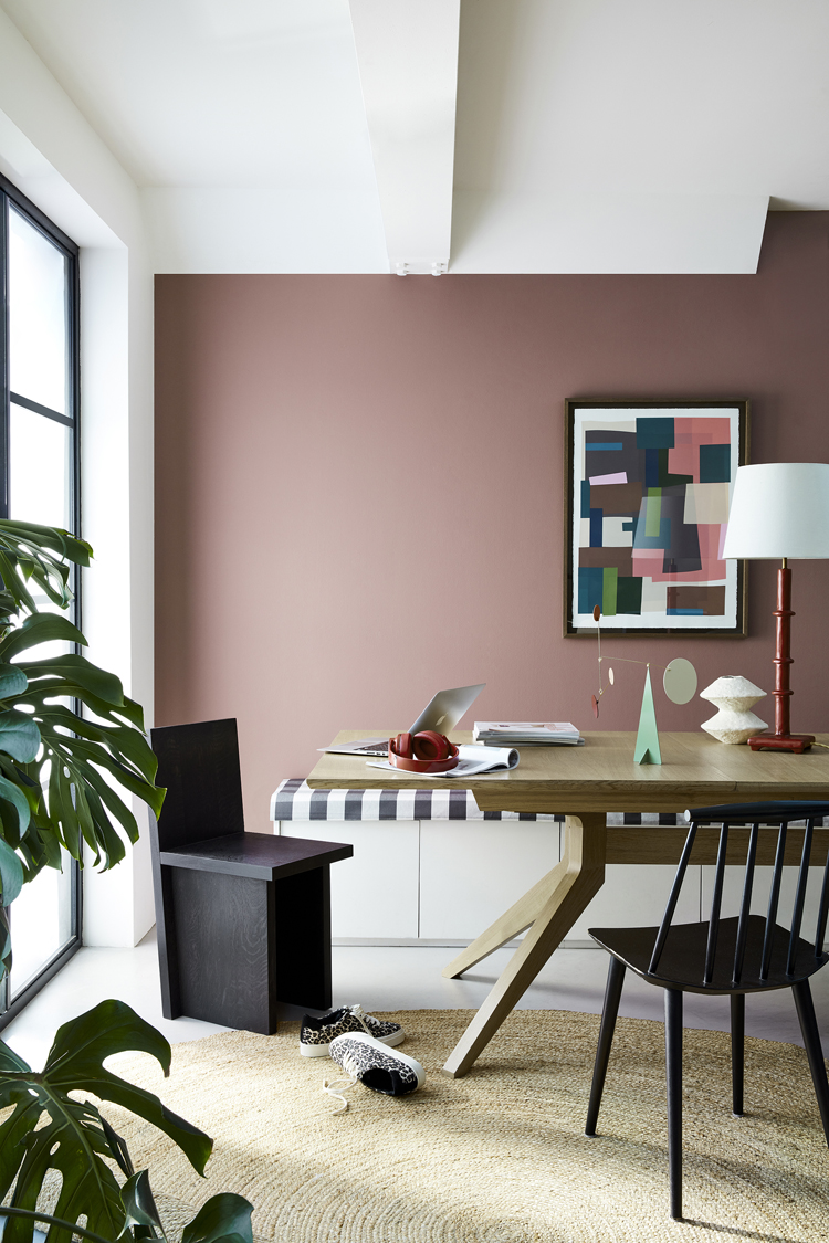 Modernes Wohnambiente mit Wand in altrosa und Esstisch davor.