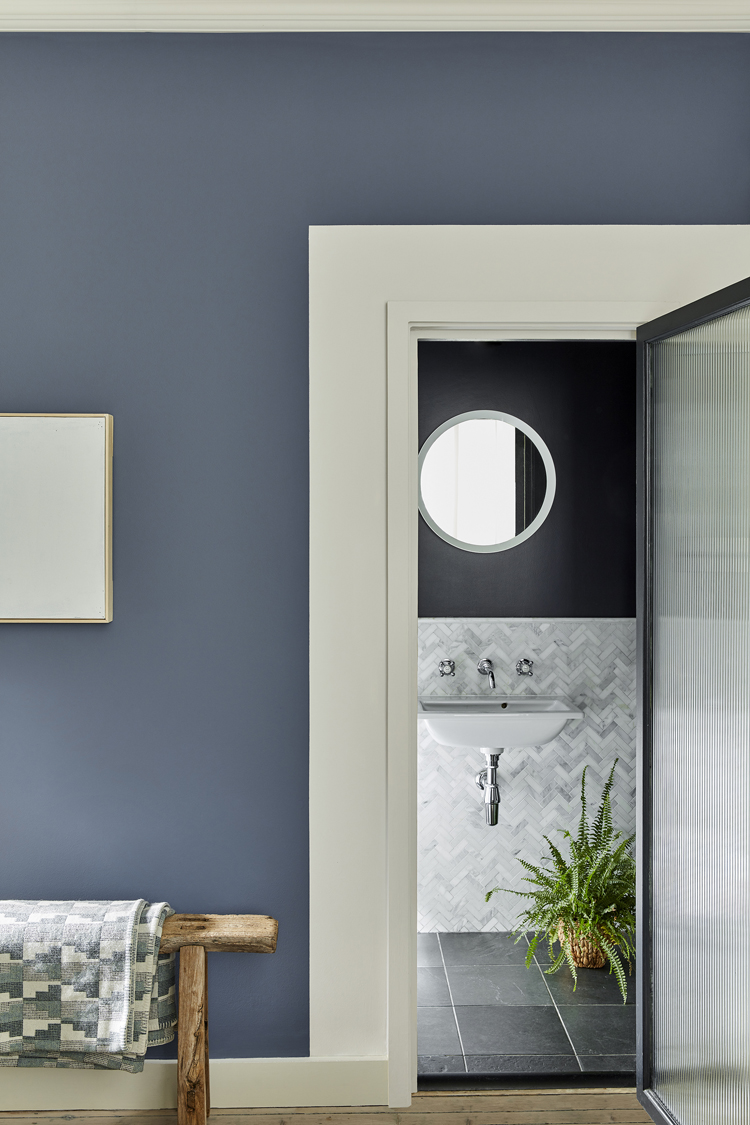 Blaue Wand mit Blick ins Badezimmer.