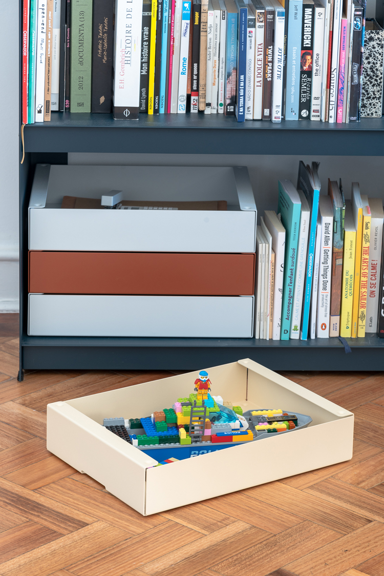 Aufbewahrungsbox steht auf Boden vor Bücherregal gefüllt mit Lego.