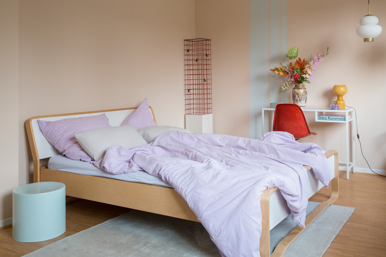 Schlafzimmer mit Holzbett und violetter Bettwäsche.
