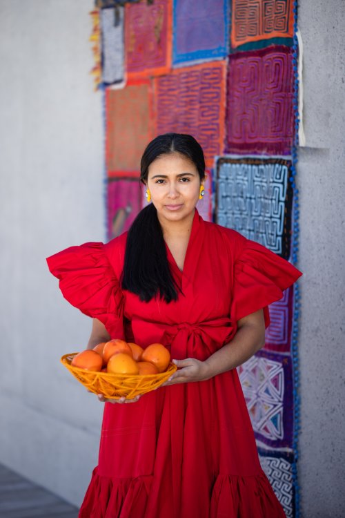 Maria Lorez in einem roten Kleid und einer Früchteschale.